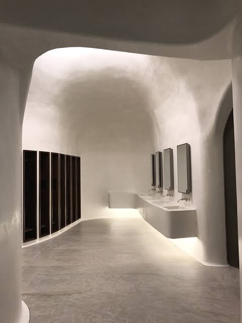 Tadelakt plaster finish on curved walls in a hallway with basins